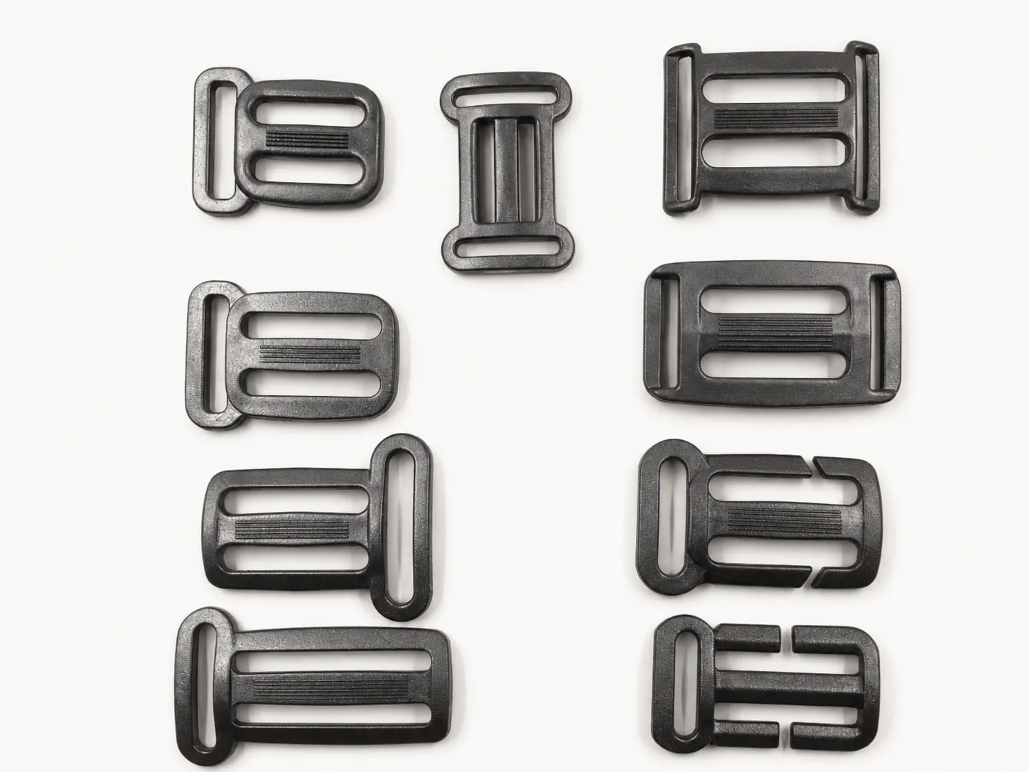 Black plastic strap adjusters ladder locks and slider hardware on white background